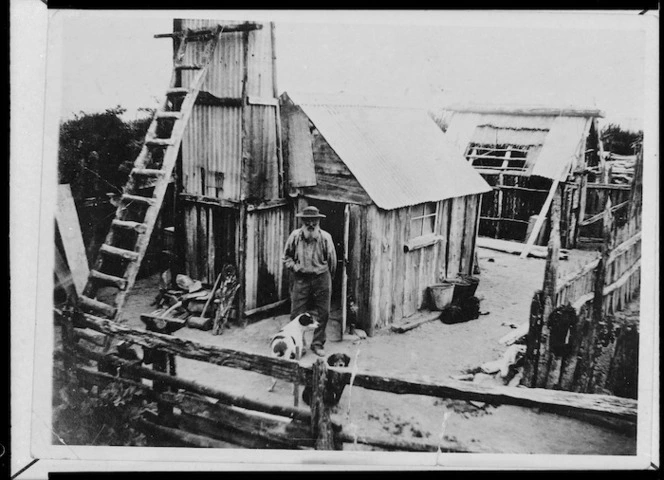 Peart, Heaton Clairemont, 1894-1991: Photograph of gold miner Piggery Charlie outside his hut at Waiho Gorge, West Coast