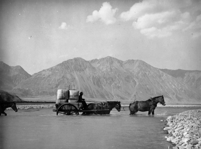 Bales of wool being transported by horse drawn cart across the Rakaia River