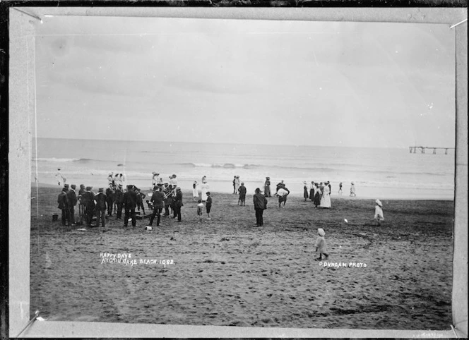 Crowd of people, including a brass band, at the beach at Opunake - Photograph taken by David Duncan