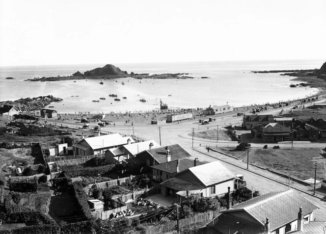 View over Island Bay, Wellington, showing houses, V Barnao's grocery and fruit store, the beach, and over to Tapiteranga Island