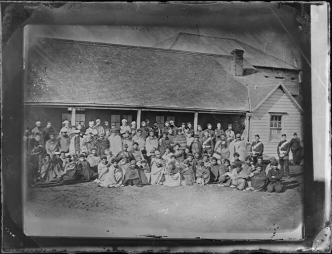 Rutland Stockade, Whanganui, with a large group of Maori wearing blankets and soldiers in uniform