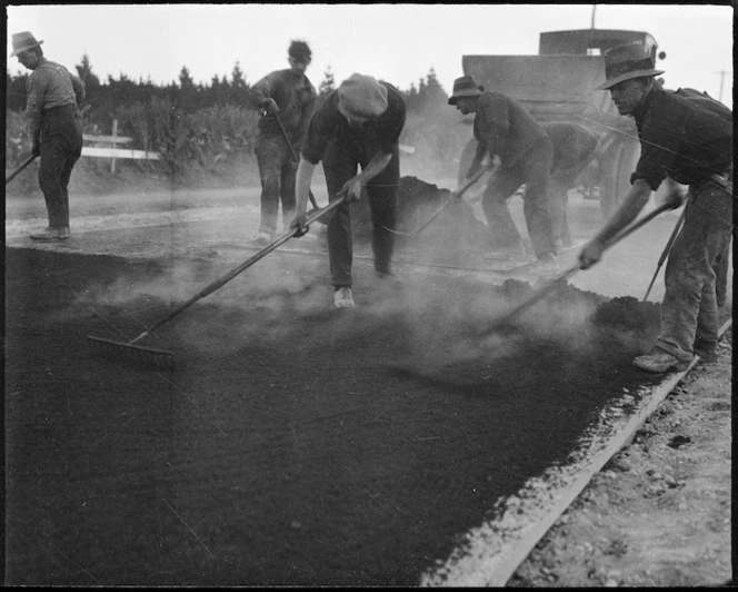 Men laying tar during the construction of a road