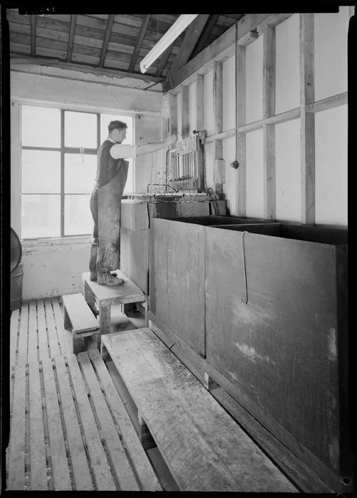 Factory worker preparing metal parts for dipping in tank