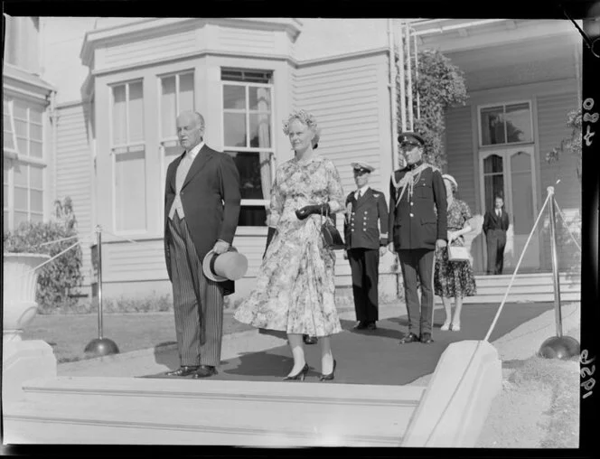 Governor General Sir Willoughby Norrie and Lady Patricia Merryweather Norrie move from the house to the lawn during a garden party at Government House, Wellington, including military uniforms, dresses, headpieces, top hats, and striped pants