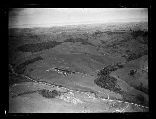 View of Kirkup's Farm with a road, farm buildings and rolling farmland, Auckland