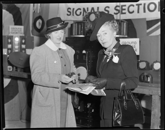 Unidentified women standing in front of radio and signals display, Battle of Britain week parade, unknown location