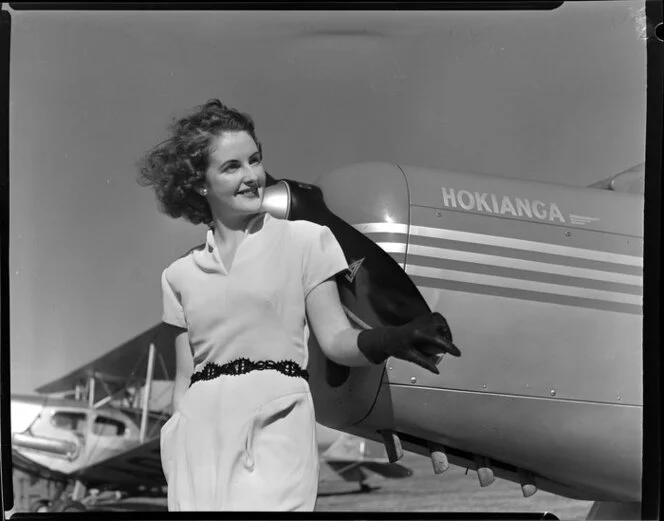 Royal New Zealand Air Command RAC Pageant at Mangere, Miss Dorothy Pollard standing in front of Eric Gray's Auster aircraft Hokianga