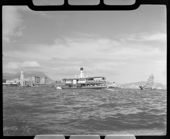 Star Ferry, a passenger service, and a junk on Victoria Harbour, between Kowloon and Hong Kong Island, with Kowloon Railway Station in the background