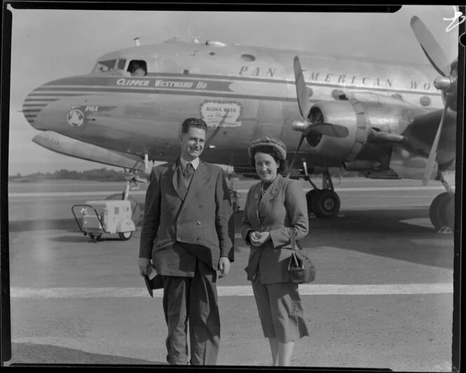 Passengers Harold and Annie Hills, having arrived on a Pan American World Airways flight, stand in front of Douglas DC-4 Clipper Westward Ho (N88948) at Whenuapai aerodrome, Waitakere City, Auckland