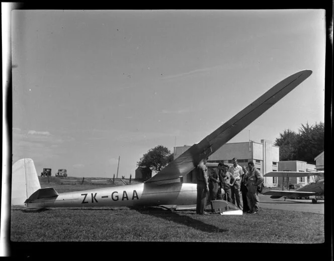 Mr G Hookings and a group of unidentified men standing next to his glider at Mangere, Auckland