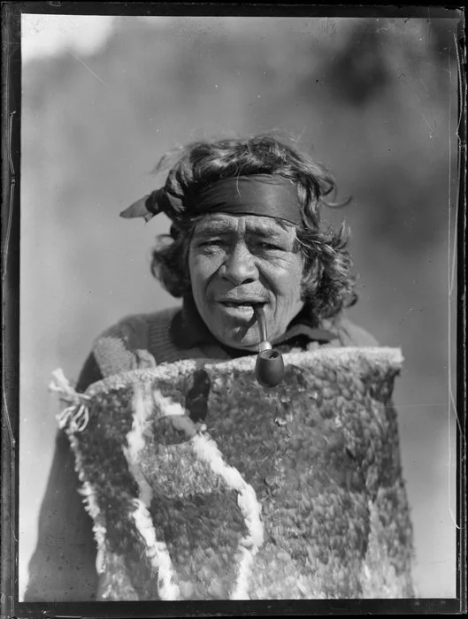 Portrait of Maori kuia Marutuna of Orakei Korako smoking a pipe and wearing a traditional feather cloak