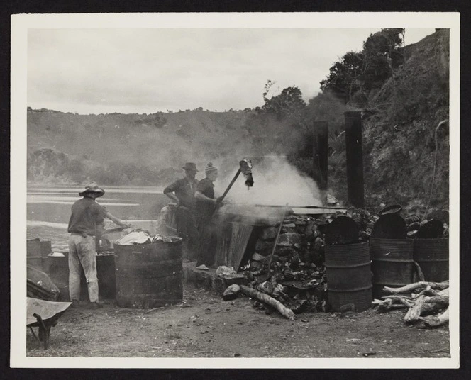 Three men boiling blubber in cauldron with processing barrels in the foreground