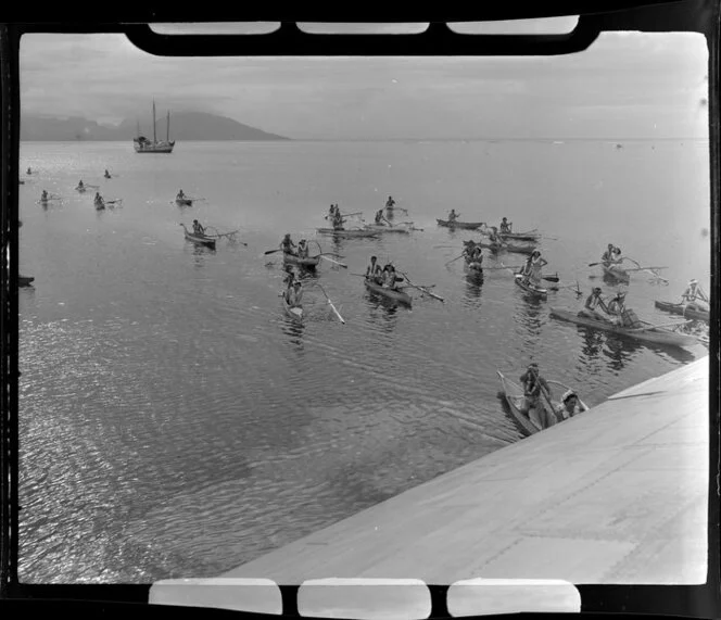 Locals greet flying boat in canoes, Tahiti, showing boat in background