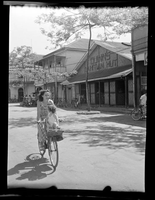 Street scene with woman riding bicycle with toddler, Papeete, Tahiti