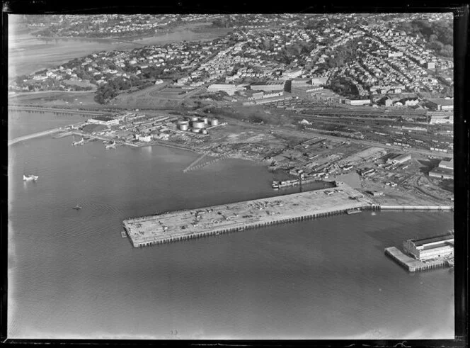 Auckland City water front, showing new wharf area under construction with float plane on harbour, Tamaki Drive and Quay Street, railway yard, views to Parnell and Hobson Bay beyond