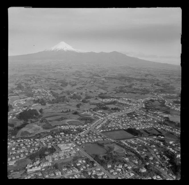 View over New Plymouth, Taranaki District, outer suburbs looking inland with soccer and rugby grounds among residential housing, Tukapa Street, farmland and Mount Taranaki beyond