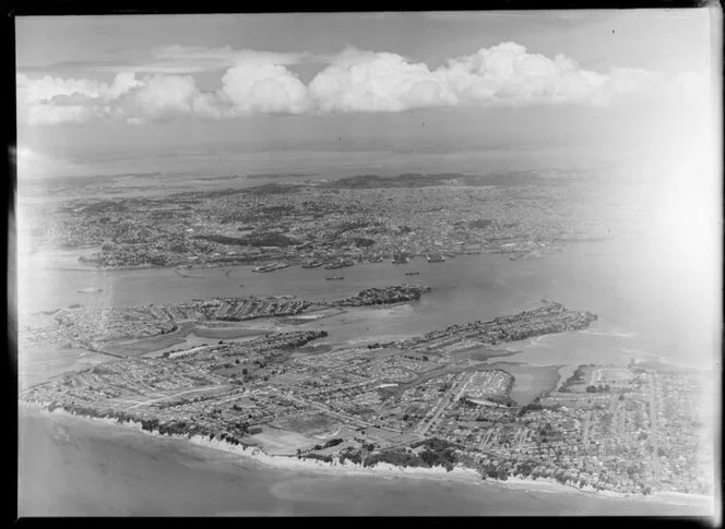 North Shore (foreground), Auckland wharves and harbour (centre), Manukau Harbour in the distance