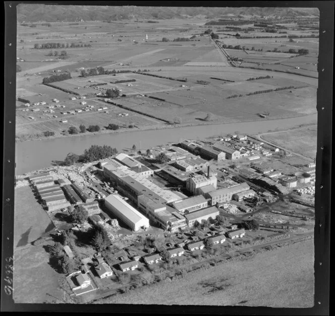 Whakatane Board Mills, Whakatane, Bay of Plenty, closeup view of wood pulp processing plant besides the Whakatane River, with farmland beyond