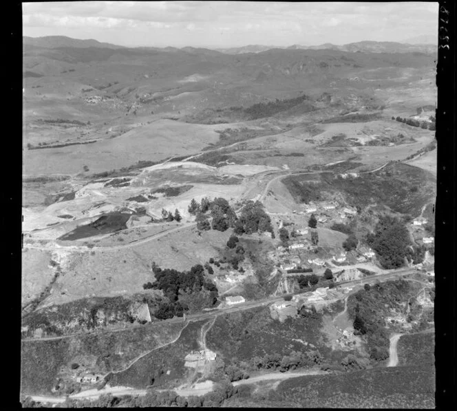 Pukemiro, Waikato, showing railway line with coal bins on side of hill between residential houses, with open caste coalmine on top of hill, farmland beyond