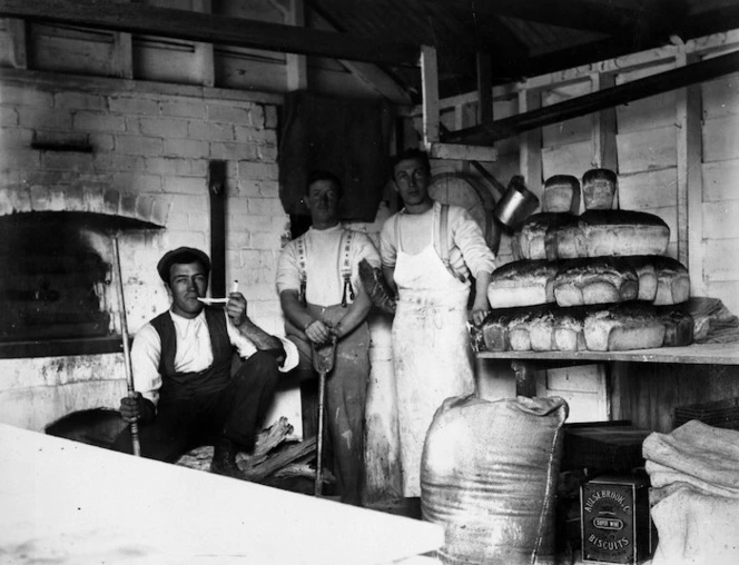 Three bakers next to a stack of bread, Rangiora