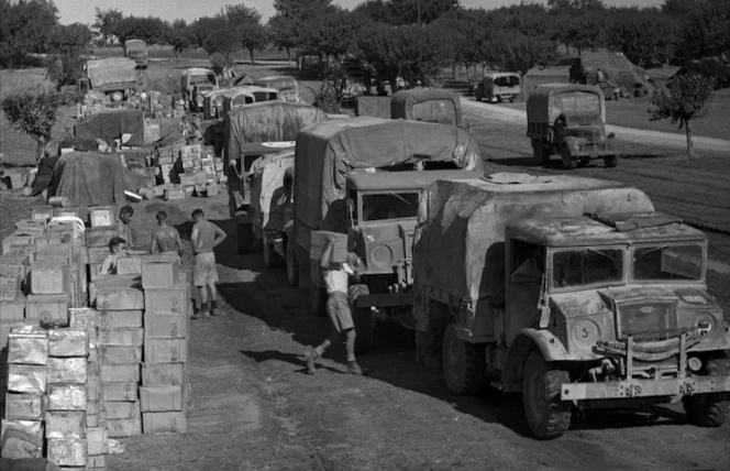 Unit trucks lined up at New Zealand Division Supply Point, waiting for unit rations to be loaded up for delivery