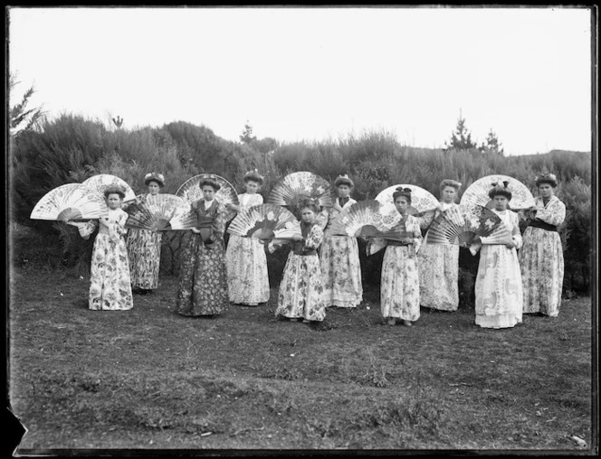 Girls wearing floral dresses and holding Japanese fans