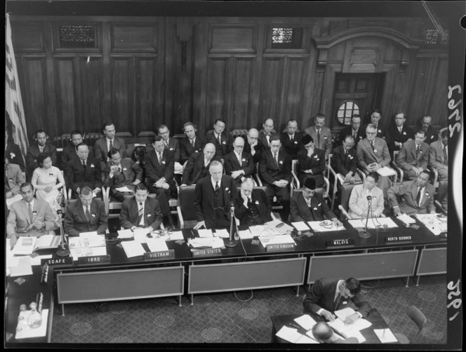 The unidentified United States representative addresses the Colombo Plan conference in Wellington, during the opening ceremony, including representatives from Vietnam, United Kingdom, Malaya, North Borneo, International Bank for Reconstruction and Development, and Economic Commission for Asia & the Far East