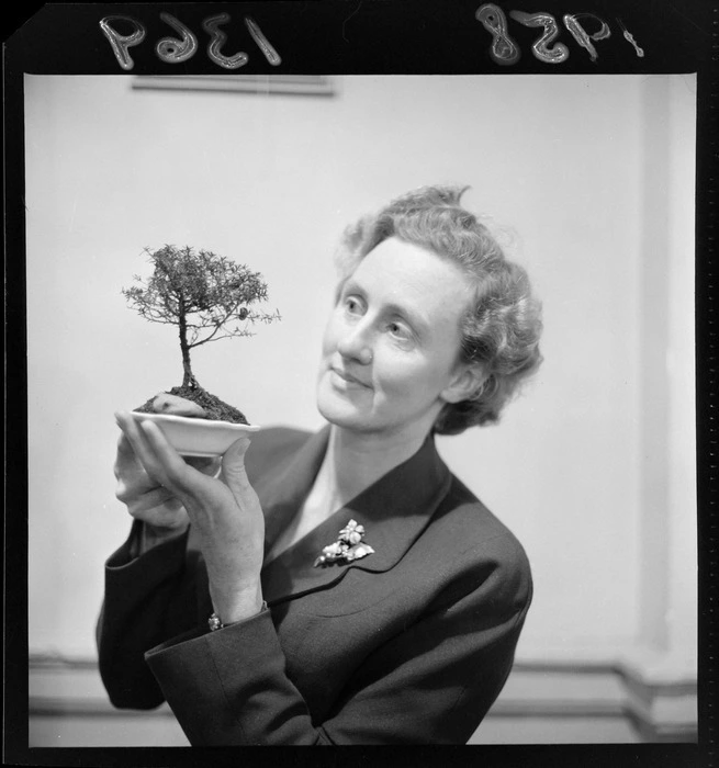 Unidentified woman holding a ming tree at an exhibition in the Wellington Town Hall