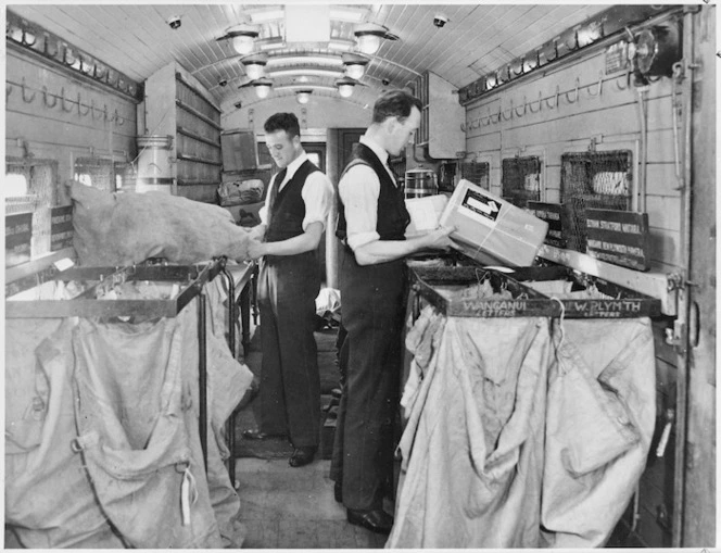 Postal workers sorting mail in a railway carriage