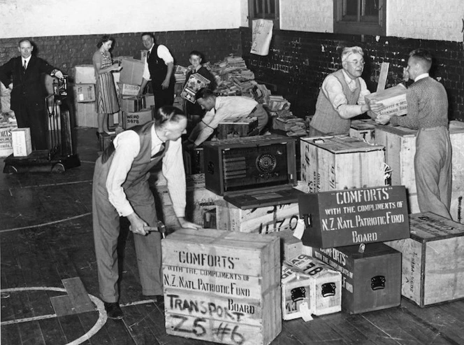 Packing and stacking cases of "comforts" for World War 2, New Zealand soldiers, YMCA gymnasium, Wellington