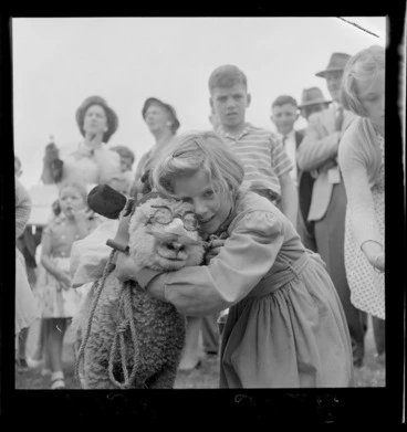 Image: Unidentified young girl with her winning pet lamb, which is wearing novelty glasses with nose and moustache, Palmerston North Agricultural & Pastoral Show (A & P Show), Manawatu-Whanganui Region