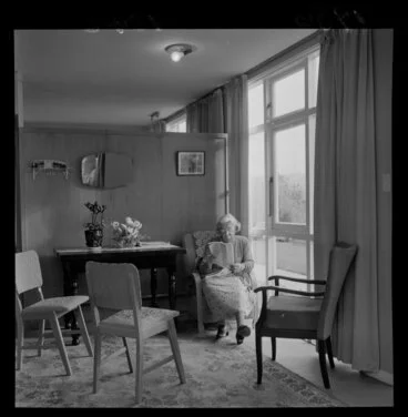Image: An unidentified female resident of Wesley Old Peoples' Home, sitting by a window, reading