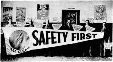 Image: Evening Post" Photo. "Safety First" pennant to be flown from the Town Hall from Monday in connection with "Safety Week." It ivill be kept at the masthead as long as no serious accident occurs, and loivered to half-mast if the clean record is broken. Behind those holding the flag are a number of triangular signs to be carried on cycles. (Evening Post, 03 December 1938)