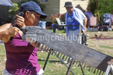 Image: Maori female competitor in the womens single handed wood sawing competition at the woodchopping events.