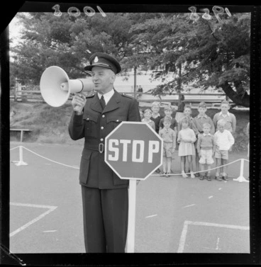 Image: Traffic training, Karori School, Wellington, traffic warden showing children about using the STOP sign