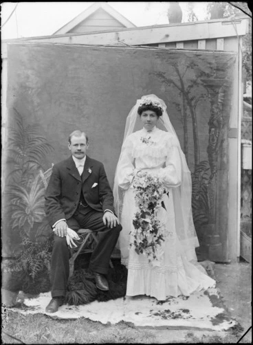Image: Unidentified bride and groom outdoors, with a painted studio backdrop, probably Christchurch district