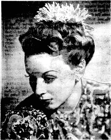Image: A :floral'tfteme is co-ordinated with many smart and original coiffures, as witness Helen Hunt's hairstyle posed by loan Perry, Columbia star. Severely drawn back, sculptured curls are set off ivith a spray of chrysanthemums, rolls on the temples and pin curls to the centre back. (Evening Post, 11 May 1940)