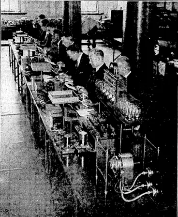 Image: The Murray Multiplex Printing Set enables four rne^sages, at the rate of 43^ords per minute, to be sent in each direction over a single Hrie—a total of 344 wordi per minute. A tape is perforated by working the keyboard; and four of theW tapes are worked simultaneously into the transmitter. At the receiyihg station the signal impulses of the four messages are sorted out and the text is automatically typed put. The actual typing of a letter by the receiver takes place about a twentieth of a second after the sender has depressed the key. (Evening Post, 08 February 1935)