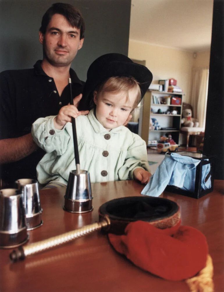 Image: Magician Roderick Mulgan watches as daughter Julia tries her hand at magic.