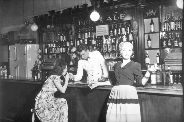 Image: Showing the interior of the Occidental Hotel, Vulcan Lane, Auckland with the barman and a couple of female patrons