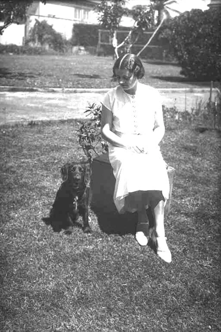 Image: Showing a woman seated in a garden with dog sitting beside her,....