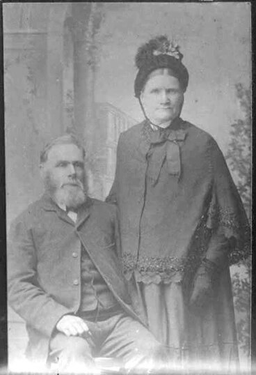 Image: 3/4 portrait of bearded man and woman, man seated wearing a....