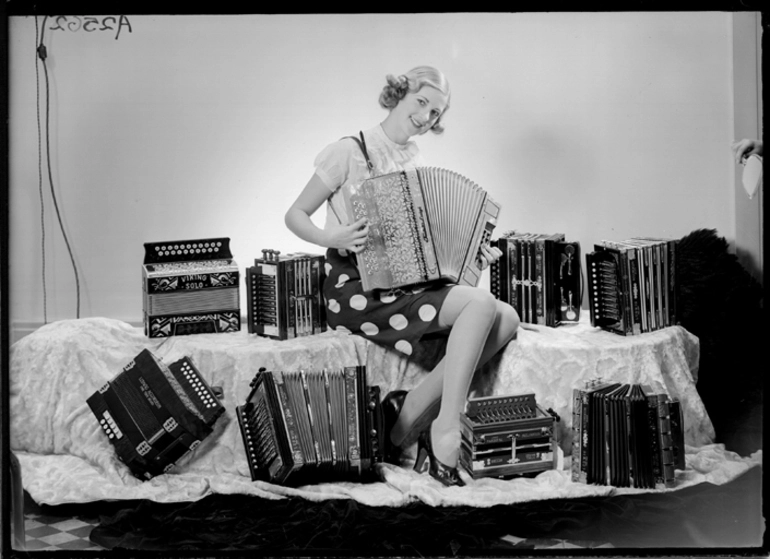 Image: Full length portrait of a model playing a button accordian for Atwaters Limited 1940
