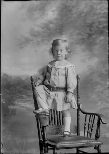 Image: Full length portrait of baby Young, standing on a wooden chair,....