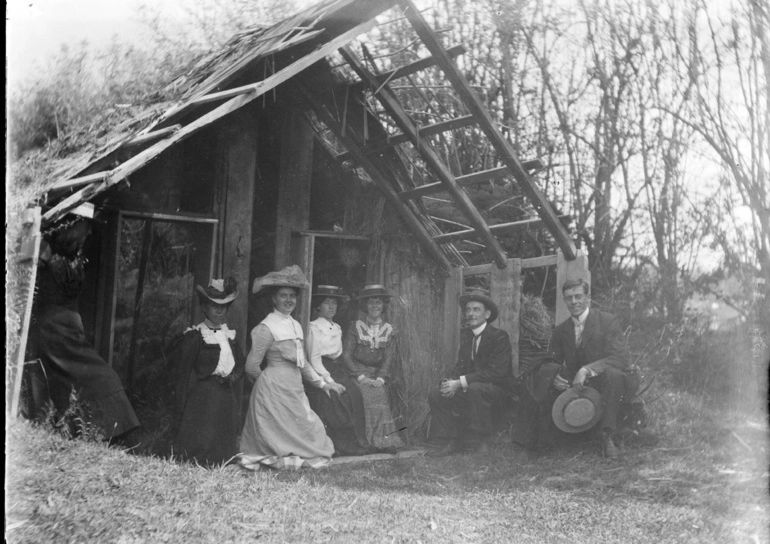 Image: A group of unidentified men and women outside Guide Sophia's ruined whare at Wairoa, March 1902