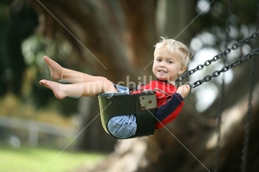 Image: a young boy enjoys a swing