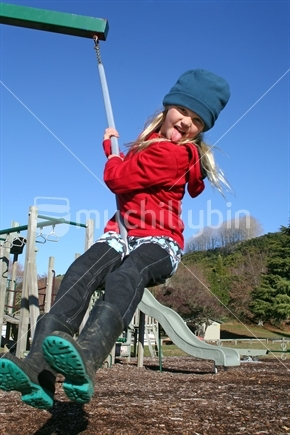 Image: School aged girl playing on a swing