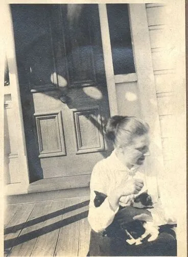 Image: Young woman with 2 cats sitting on porch.