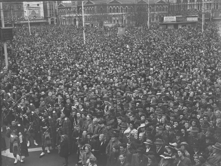 Image: Celebrations. Crowd at WWII, Victory over Europe ( VE ) Day Celebration. Held 9 May 1945, With Flags and Pipers. Cathedral Square, Christchurch, Canterbury, New Zealand.