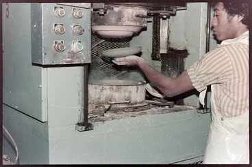 Image: Negative - Man preparing to apply clay to a press moulding machine